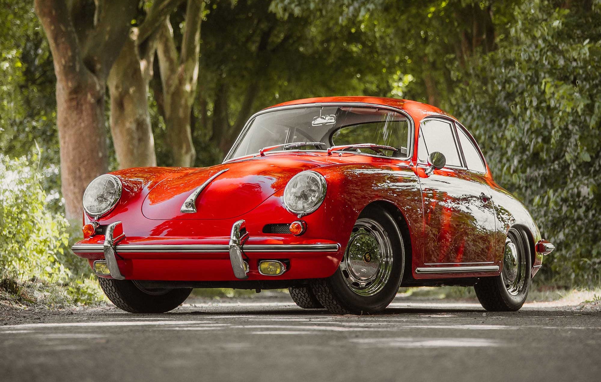 Top restaurierter roter Porsche 356 Oldtimer auf einer Alleestraße – Beispielfahrzeug für ein Wertgutachten bei AUTONORM