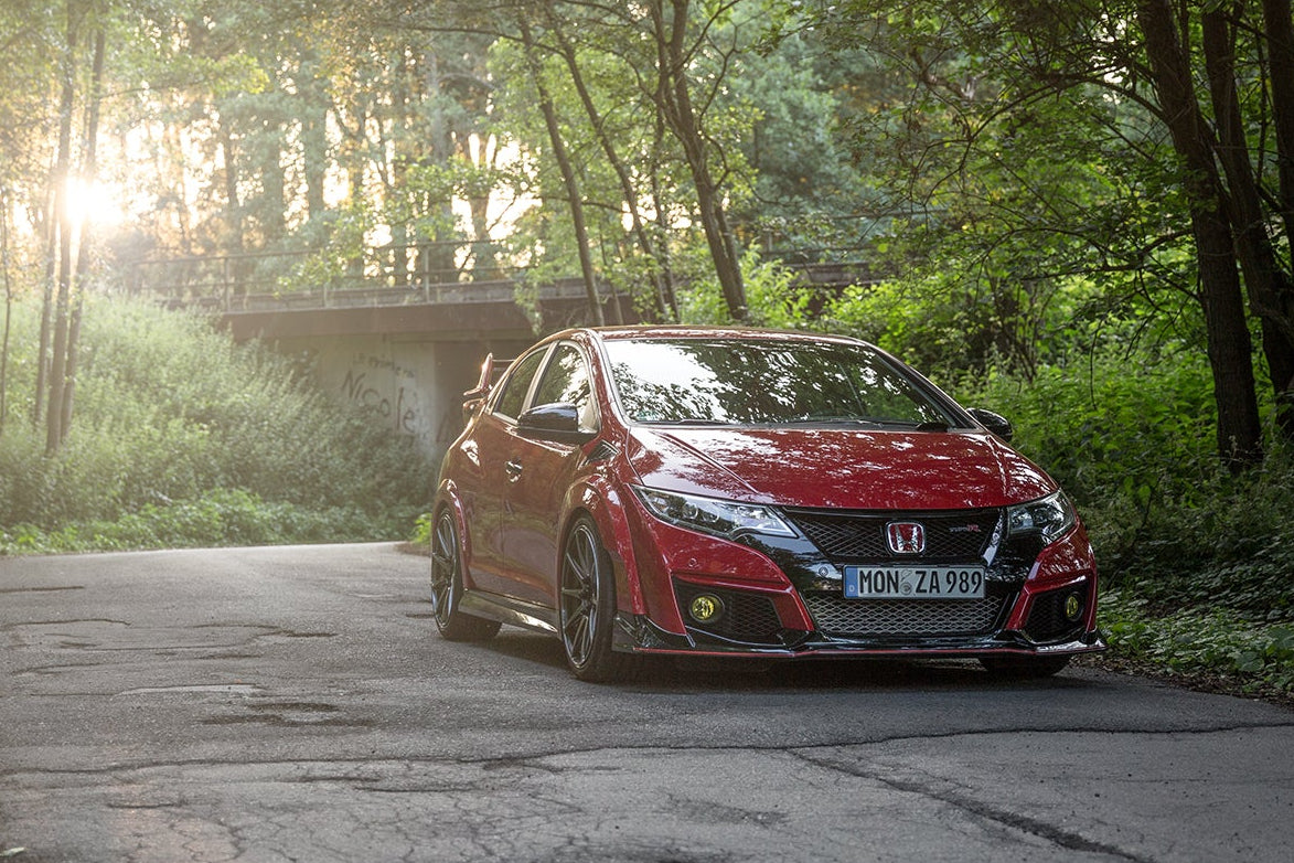 Roter Honda Civic Type R auf einer Waldstraße bei Sonnenuntergang – Beispielfahrzeug, bei dem sich ein Gebrauchtwagencheck vor dem Kauf besonders lohnt.